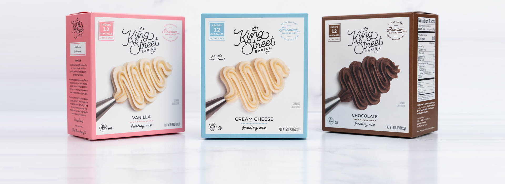 Three boxes of King Street Baking Co frosting mix on a white marble background.